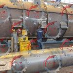 تصویری از یک کوره صنعتی با درب باز، نشان دهنده قطعات فلزی در حال عملیات حرارتی با نور نارنجی شدید و حضور تکنسین‌ها برای بازرسی فرآیند.